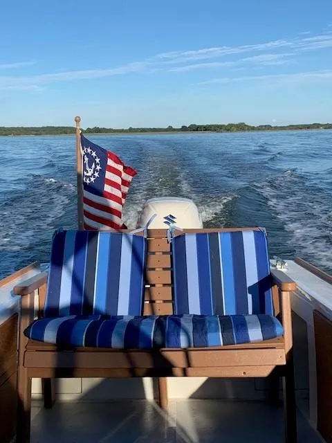 Slide: The Image of Custom Vansant 30 boat, 1987 model, with striped seating and American flag on a lake. - 2