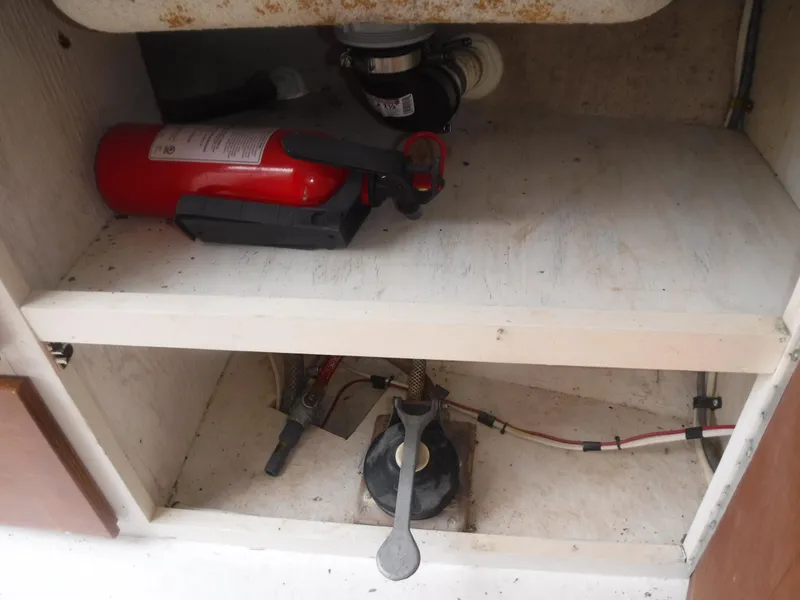 Slide: The Image of 1987 Custom Vansant 30 under-sink storage with fire extinguisher and plumbing components. - 36