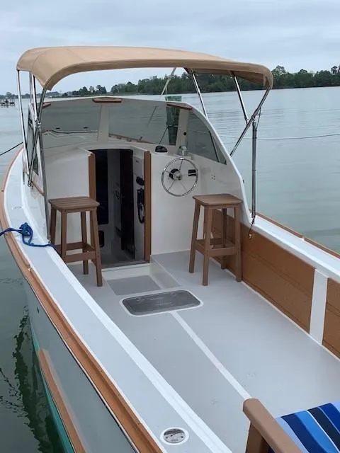 Slide: The Image of 1987 Custom Vansant 30 boat with canopy and wooden stools on calm water. - 6