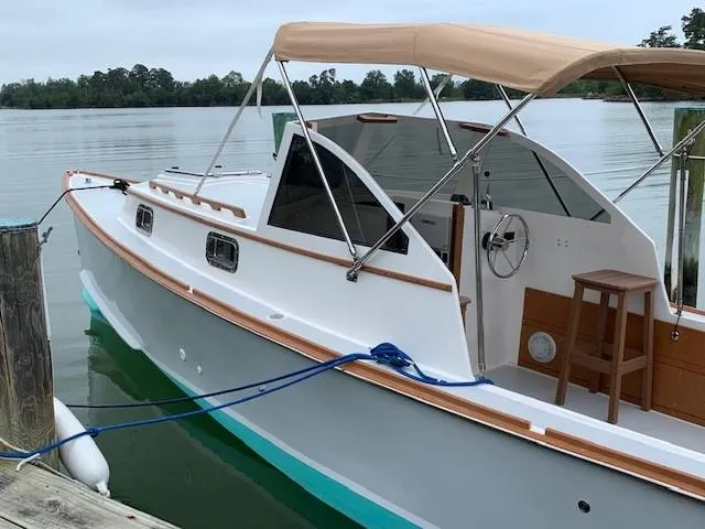 Slide: The Image of Custom 1987 Vansant 30 boat docked on a calm lake with a beige canopy. - 7