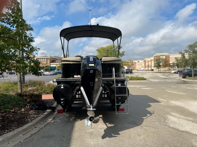 Slide: The Image of 2023 Regency 230 LE3 pontoon boat parked in a lot under a blue sky. - 2