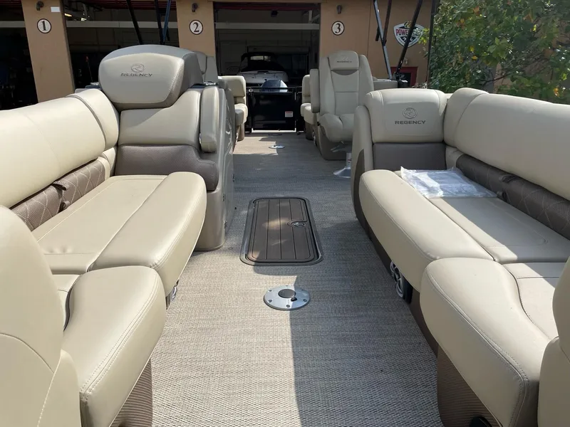 Slide: The Image of 2023 Regency 230 LE3 pontoon boat interior with beige seating and spacious layout. - 6