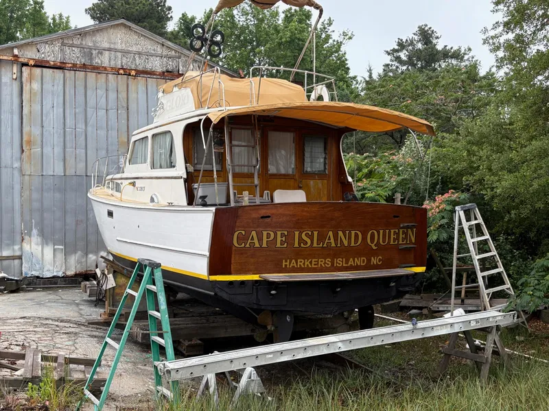 The Image of 1963 Egg Harbor Convertible Cruiser boat on dry dock near a metal building. - 0