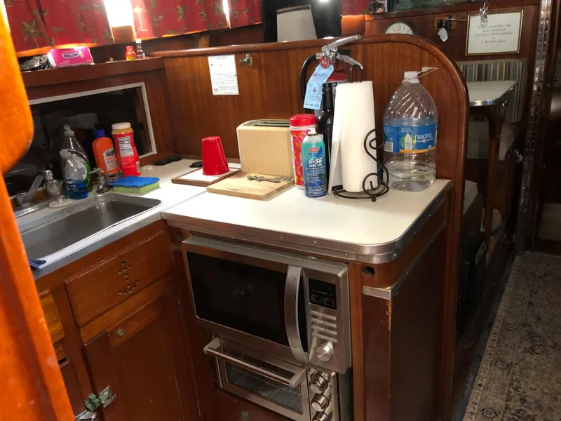 Slide: The Image of 1963 Egg Harbor Convertible Cruiser kitchen with microwave, sink, and countertop essentials. - 20