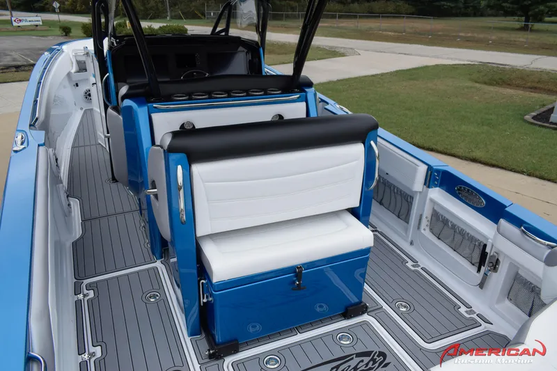 Slide: The Image of 2025 Nor-Tech 390 Sport boat interior with blue and white seating, gray flooring, and American logo. - 9