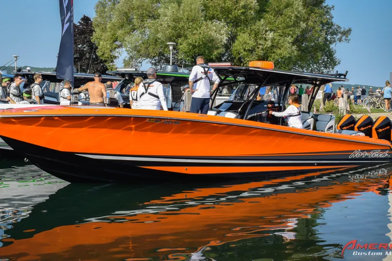 Slide: The Image of 2026 Nor-Tech 390 Sport boat in vibrant orange, docked with people onboard and nearby. - 1