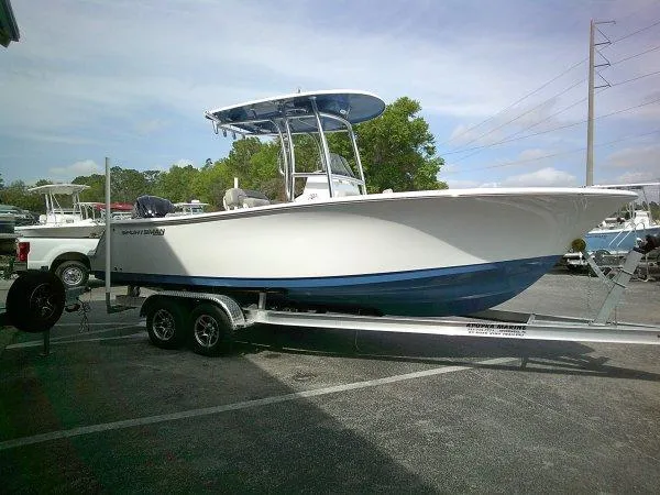 Slide: The Image of 2023 Sportsman 232 Open boat on trailer, parked outdoors, featuring a sleek white and blue design. - 12