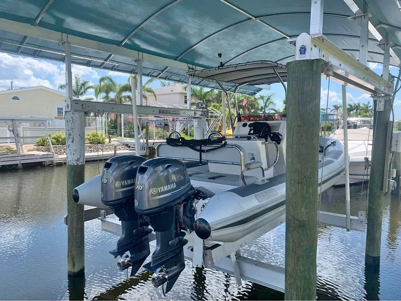 Slide: The Image of Ballistic RIB 2021 boat with twin Yamaha outboard motors on a lift in a marina. - 1
