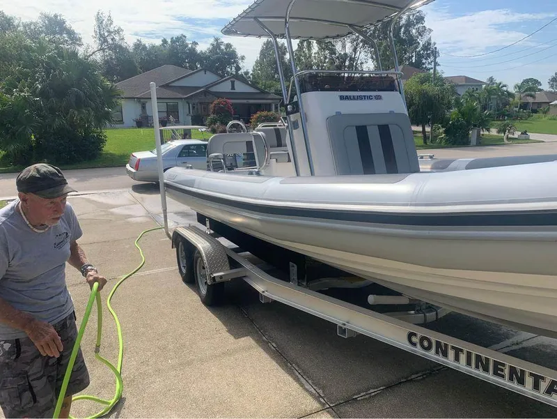 Slide: The Image of Man washing a 2021 Ballistic RIB boat on a Continental trailer in a residential driveway. - 10