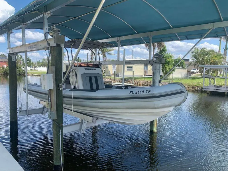 Slide: The Image of 2021 Ballistic RIB boat on a lift under a blue canopy by a canal. - 5