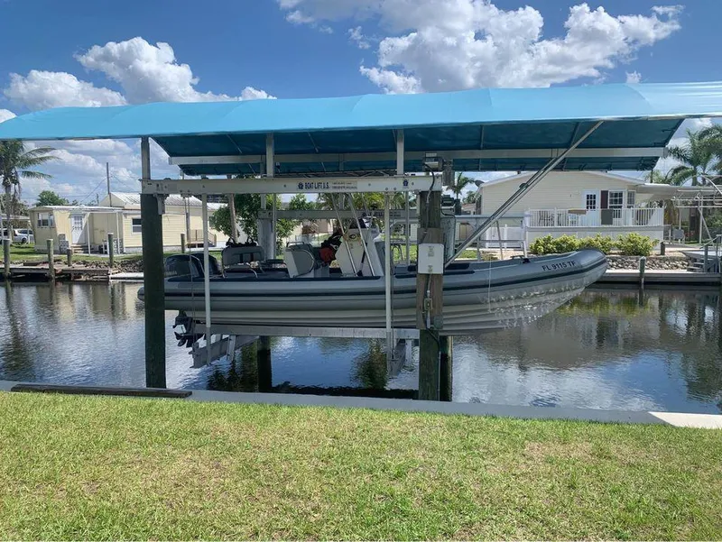 Slide: The Image of Ballistic RIB 2021 boat on a lift under a blue canopy by a canal. - 7