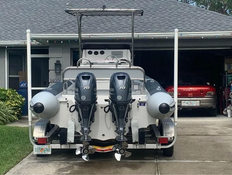 Slide: The Image of 2021 Ballistic RIB boat with twin 70 HP engines parked in a driveway. - 8