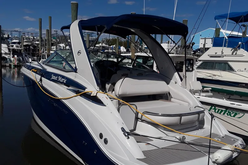 Slide: The Image of 2021 Crownline 264 CR boat docked at marina with blue canopy. - 2