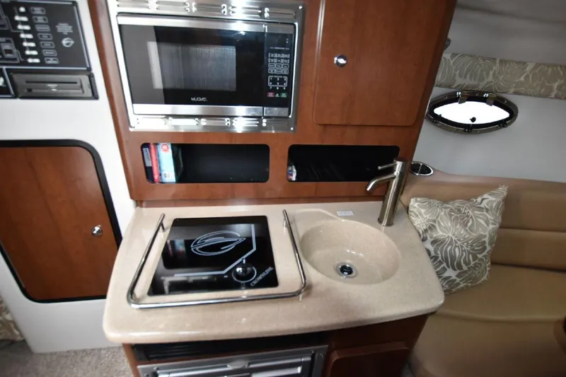 Slide: The Image of Compact kitchen area in a 2021 Crownline 264 CR boat with microwave, sink, and stove. - 4