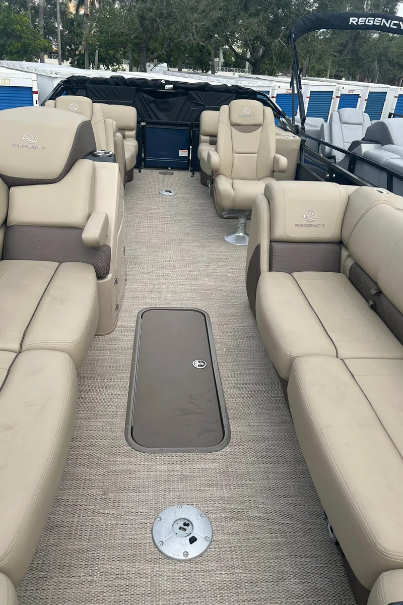 Slide: The Image of Interior of 2023 Regency 250 LE3 pontoon boat with beige seating and carpet flooring. - 9