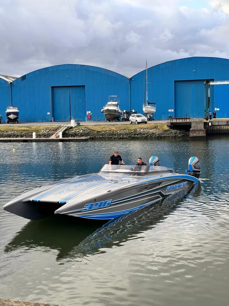 Slide: The Image of 2025 Statement 396 Cat powerboat on water near blue warehouses. - 6