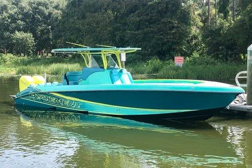 Slide: The Image of 2026 Statement 35 CC Open boat in vibrant teal and yellow, docked on a calm river. - 19