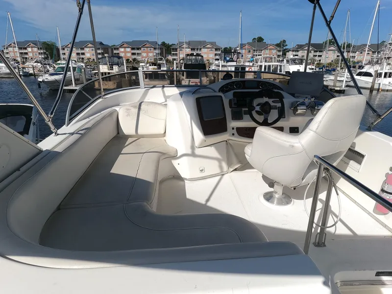 Slide: The Image of 2003 Meridian 341 Sedan yacht cockpit with white seating and steering wheel, docked at marina. - 5