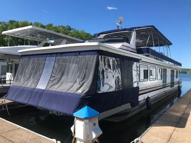 The Image of 1997 Stardust Cruisers houseboat docked, featuring blue canopy and curtains, under clear blue sky. - 0