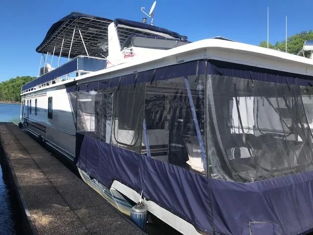 Slide: The Image of 1997 Stardust Cruisers houseboat docked, featuring blue canopy and spacious deck. - 1