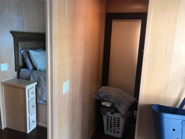 Slide: The Image of 1997 Stardust Cruisers houseboat interior with bedroom, laundry basket, and wooden paneling. - 13