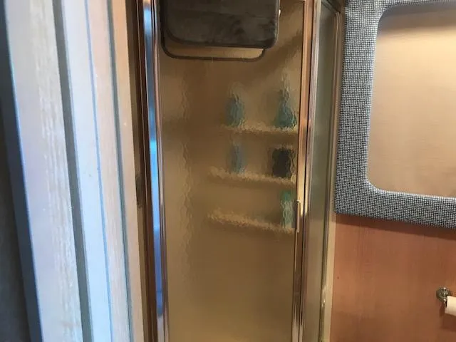 Slide: The Image of Shower area inside a 1997 Stardust Cruisers houseboat, featuring glass door and shelves. - 15