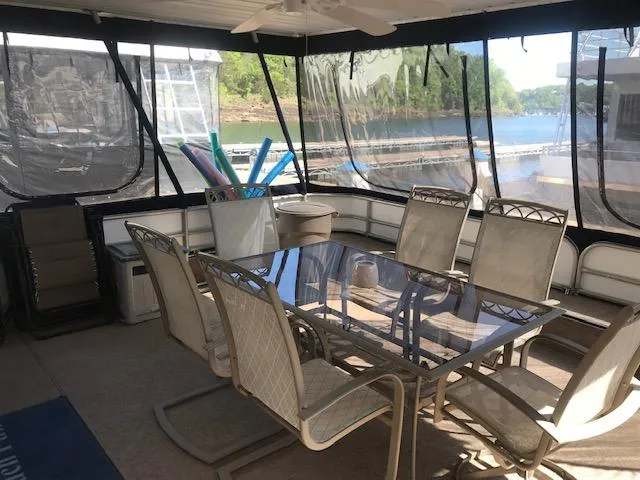 Slide: The Image of 1997 Stardust Cruisers houseboat interior with glass dining table and chairs, overlooking a serene lake. - 2