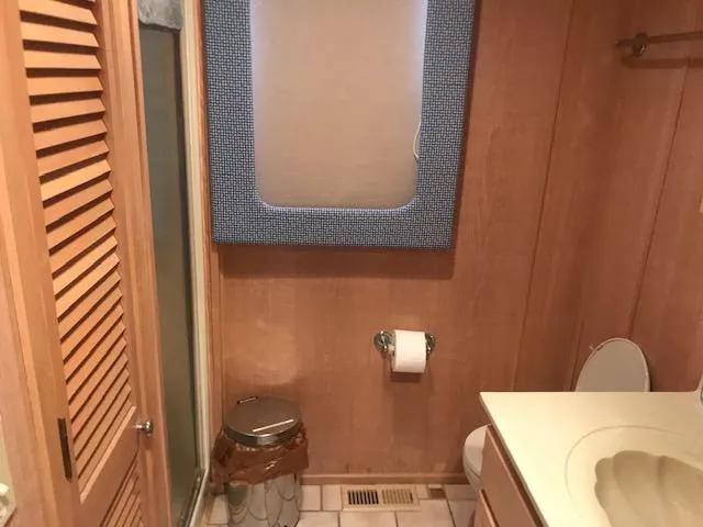 Slide: The Image of 1997 Stardust Cruisers houseboat bathroom with wooden paneling, toilet, and shower. - 20