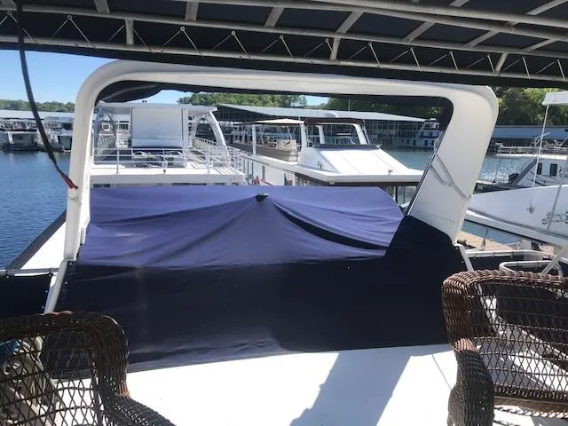 Slide: The Image of 1997 Stardust Cruisers houseboat deck with wicker chairs and covered area, docked at marina. - 31