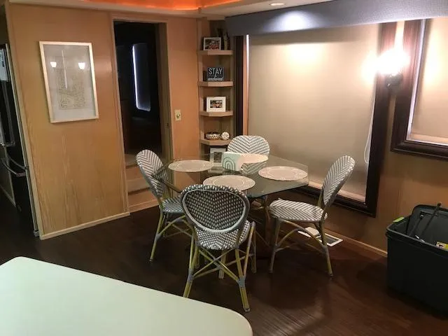 Slide: The Image of 1997 Stardust Cruisers houseboat interior with dining area, wicker chairs, and wooden flooring. - 8