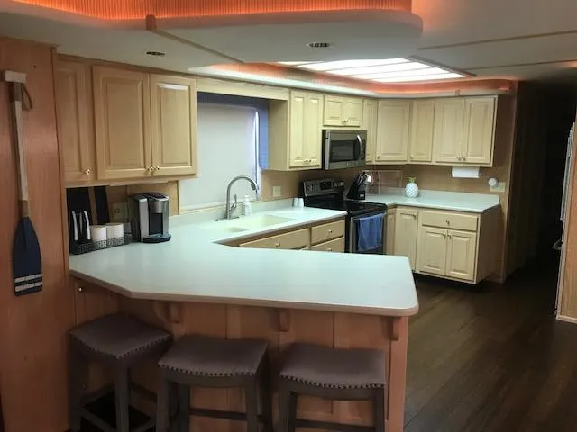Slide: The Image of Modern kitchen interior on a 1997 Stardust Cruisers houseboat with wooden cabinets and bar stools. - 9