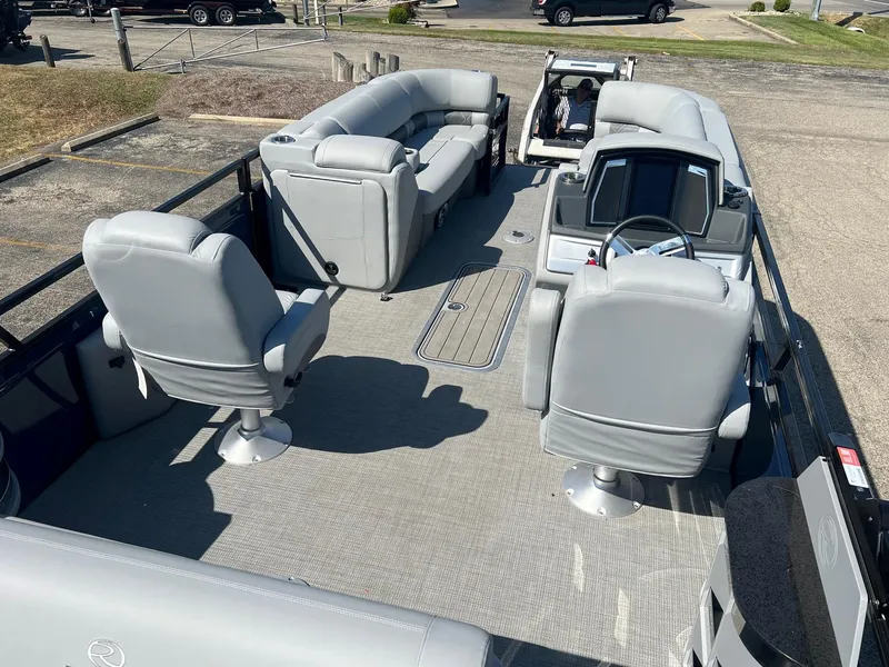 Slide: The Image of 2023 Regency 230 LE3 Sport pontoon boat interior with gray seating and steering console. - 4