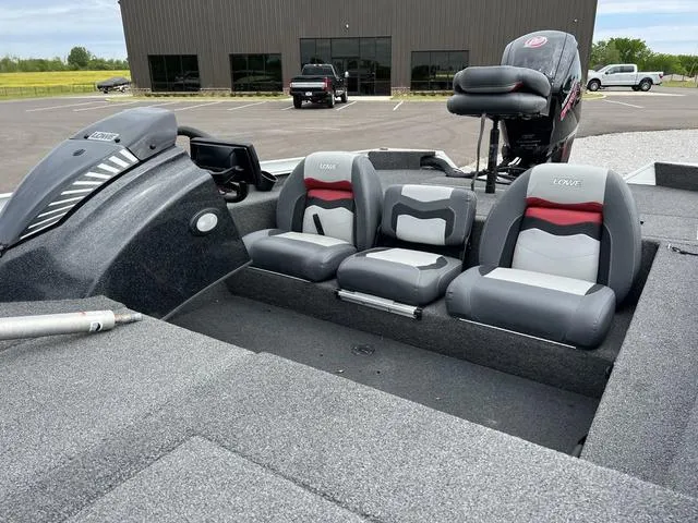 Slide: The Image of 2018 Lowe Stinger 188 boat interior with three seats and motor in parking lot. - 10