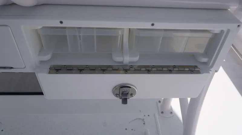 Slide: The Image of 2023 Sportsman 231 Heritage boat storage compartment with latch and plastic containers. - 11