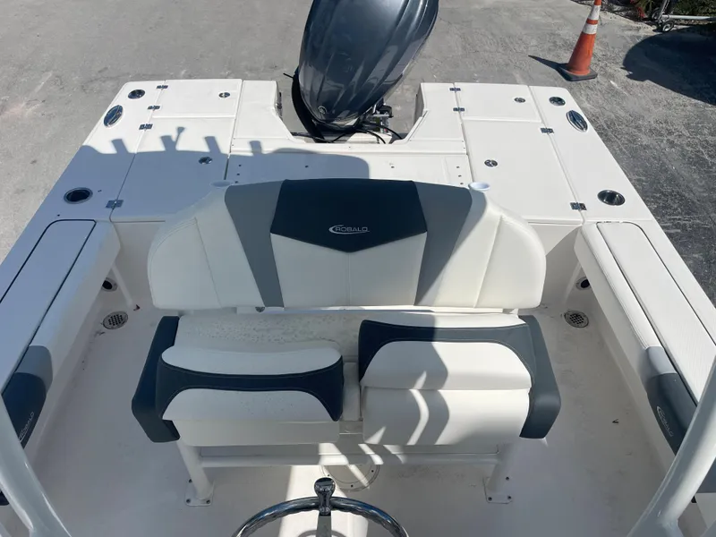 Slide: The Image of 2023 Robalo 246 Cayman boat interior with seating and motor, docked on a sunny day. - 15