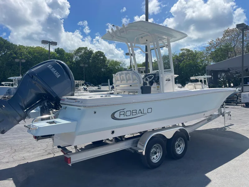 Slide: The Image of 2023 Robalo 246 Cayman boat on trailer under blue sky. - 2