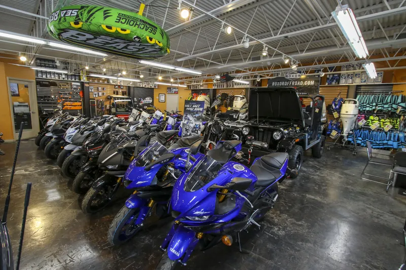 Slide: The Image of Showroom with blue motorcycles, off-road vehicles, and Robalo 246 Cayman boat equipment. - 25