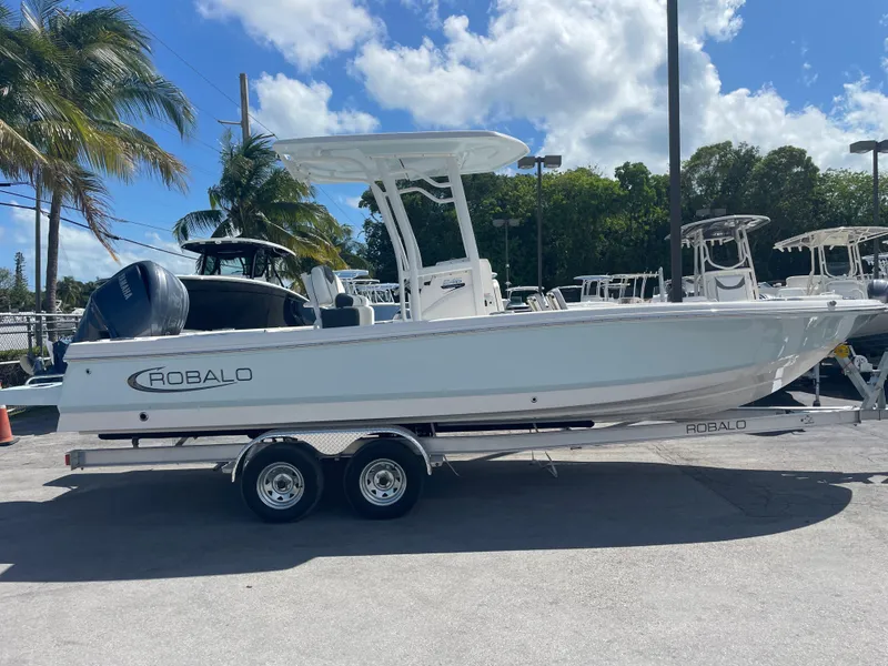 Slide: The Image of 2023 Robalo 246 Cayman boat on trailer, parked outdoors under blue sky. - 3