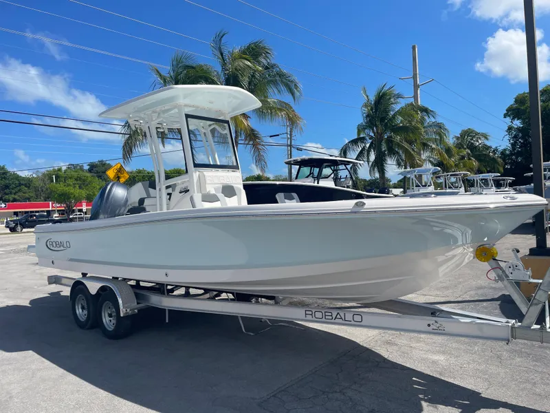 Slide: The Image of 2023 Robalo 246 Cayman boat on trailer, parked outdoors under blue sky. - 4