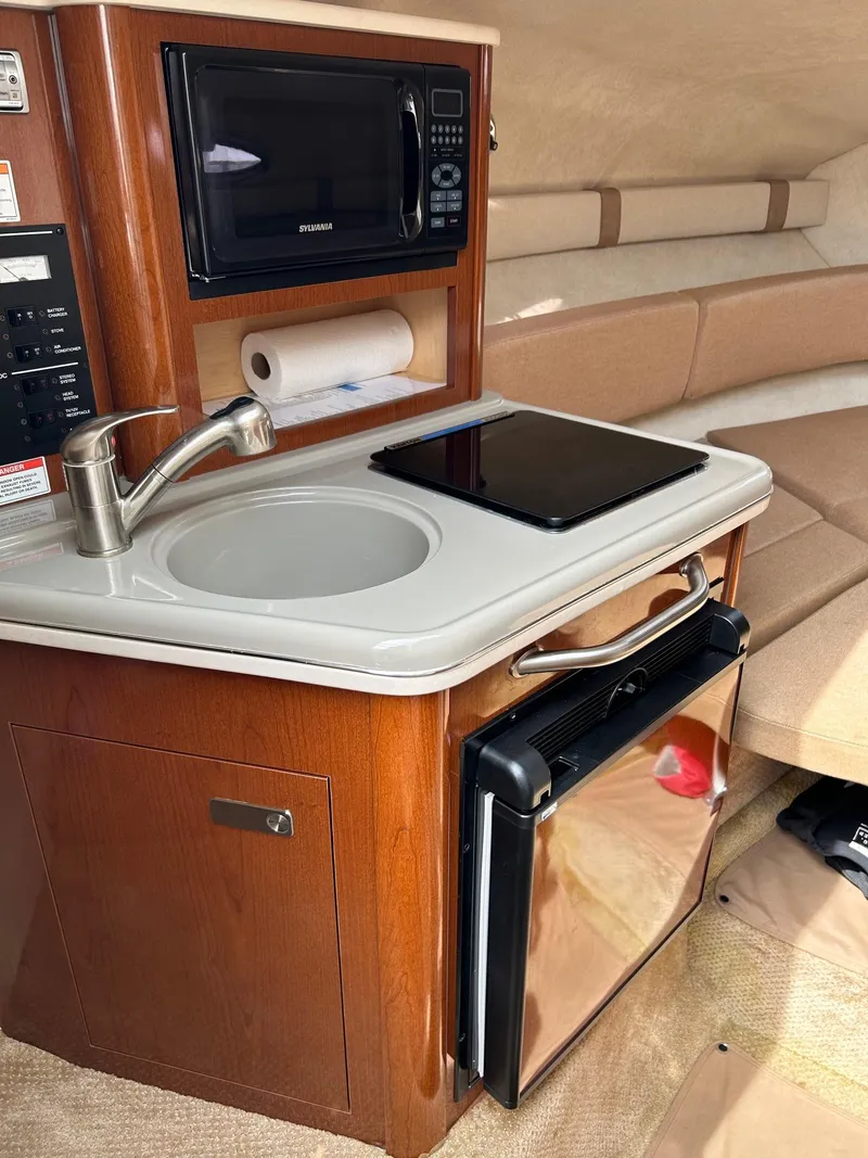 Slide: The Image of 2012 Sea Ray 240 Sundancer cabin kitchen with sink, microwave, and mini-fridge. - 27