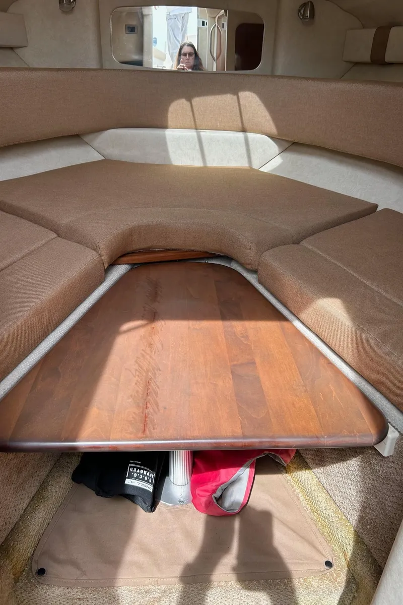 Slide: The Image of Interior cabin of a 2012 Sea Ray 240 Sundancer with a wooden table and cushioned seating. - 34