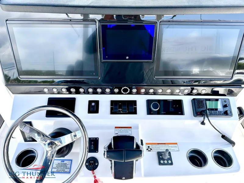 Slide: The Image of 2023 Fountain 38 CC boat dashboard with steering wheel, controls, and multiple display screens. - 14