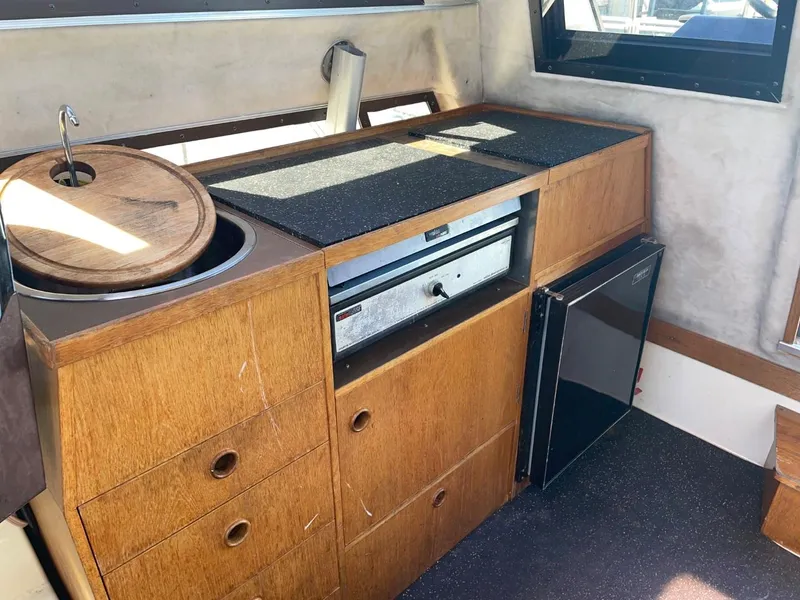 Slide: The Image of 1985 Nord West 900 boat interior kitchen with wooden cabinets and appliances. - 10