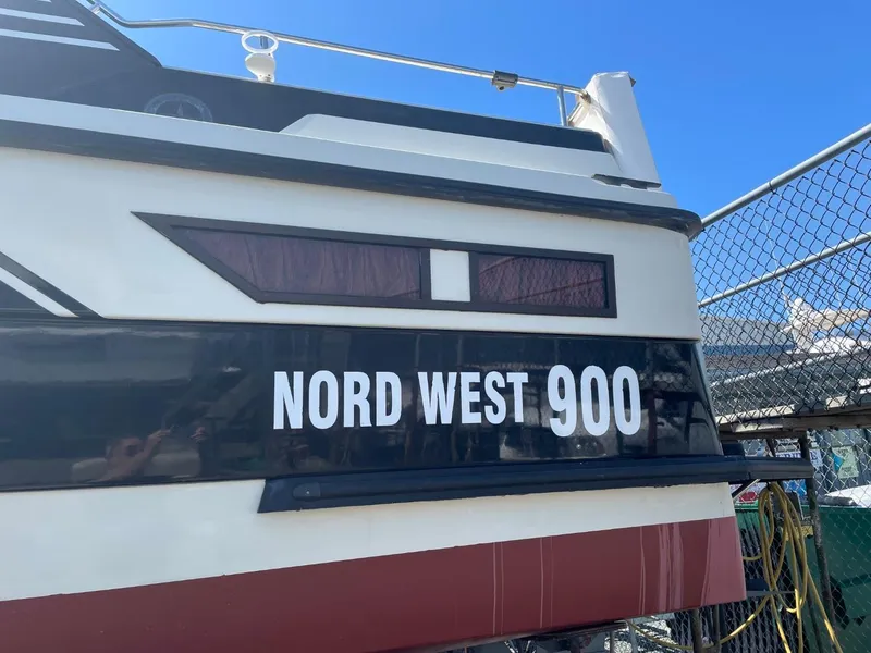 Slide: The Image of Nord West 900 boat, 1985 model, docked near a chain-link fence. - 2