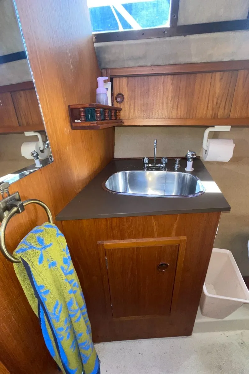 Slide: The Image of Compact bathroom in a 1985 Nord West 900 boat with wooden cabinetry and stainless steel sink. - 31