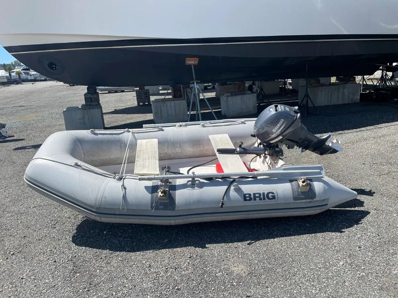 Slide: The Image of Inflatable Brig dinghy with outboard motor, parked on gravel near a Nord West 900 boat. - 38