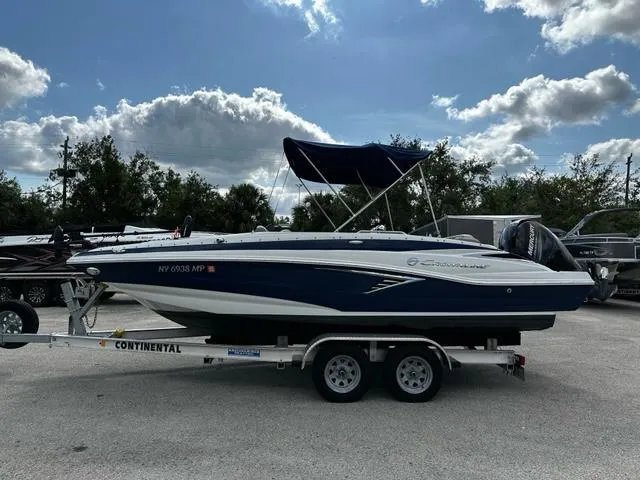 The Image of 2019 Crownline 205XS boat on a Continental trailer under a partly cloudy sky. - 1