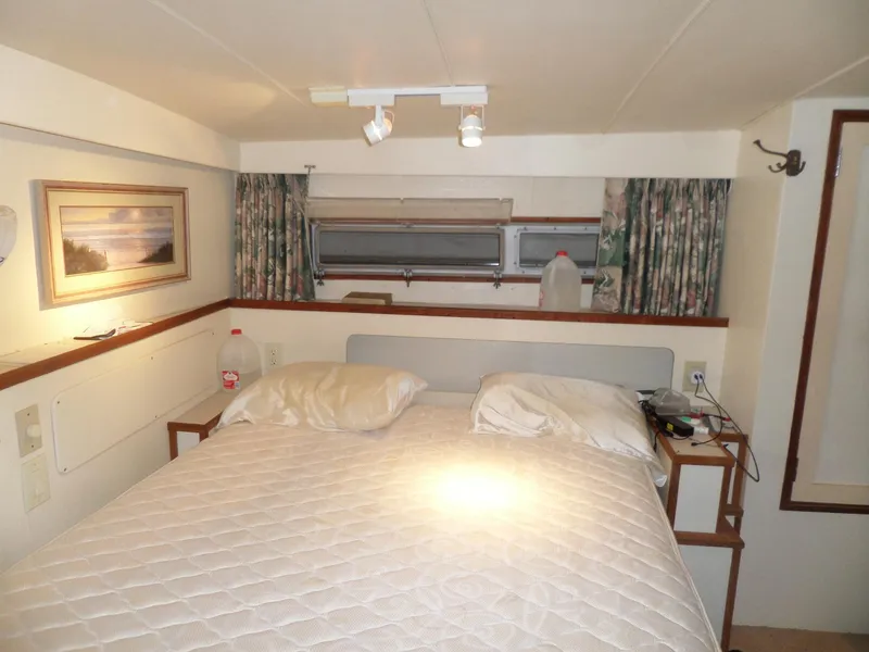 Slide: The Image of 1978 Bertram 42 Flybridge Motor Yacht bedroom with double bed, window, and wall art. - 19