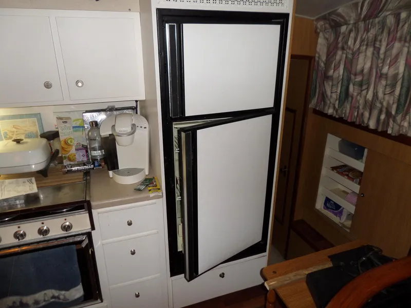 Slide: The Image of 1978 Bertram 42 Flybridge Motor Yacht kitchen with open fridge, stove, and cabinets. - 22