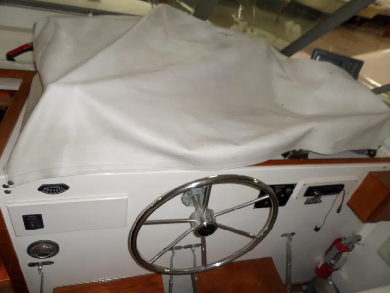 Slide: The Image of 1978 Bertram 42 Flybridge Motor Yacht helm with covered controls and steering wheel. - 41